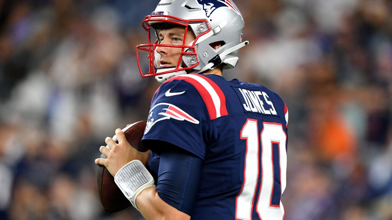 New England Patriots quarterback Mac Jones drops back to pass and looks down the field for an open receiver