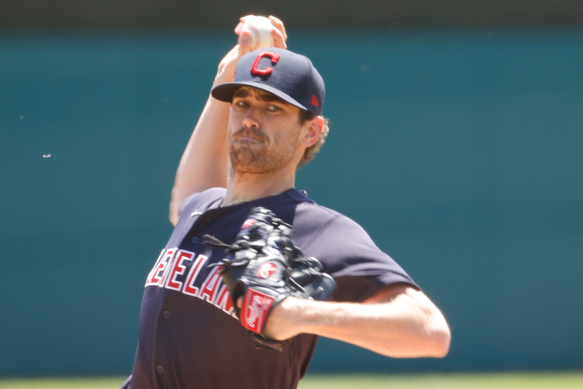 Cleveland Indians right-handed pitcher Shane Bieber reaches back over his head and prepares to deliver a pitch