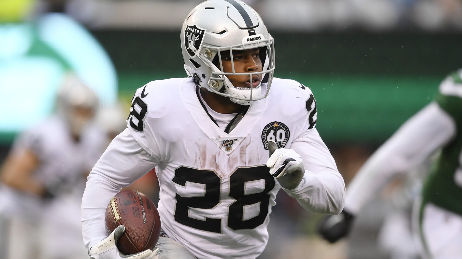 Josh Jacobs #28 of the Raiders runs the ball in a 2021 road game.