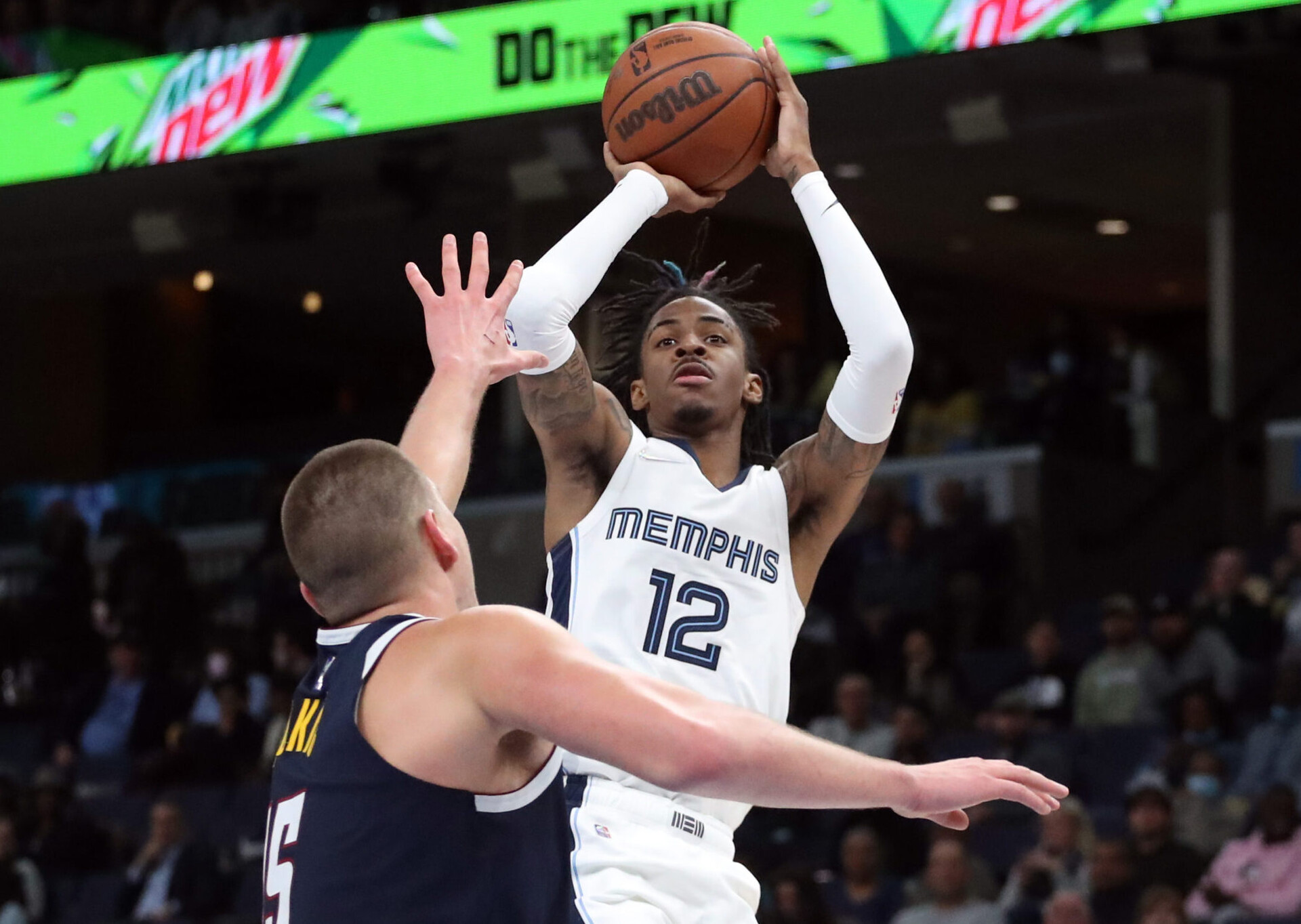 Memphis Grizzles guard Ja Morant shoots over Denver Nuggets forward Nikola Jokic in a game