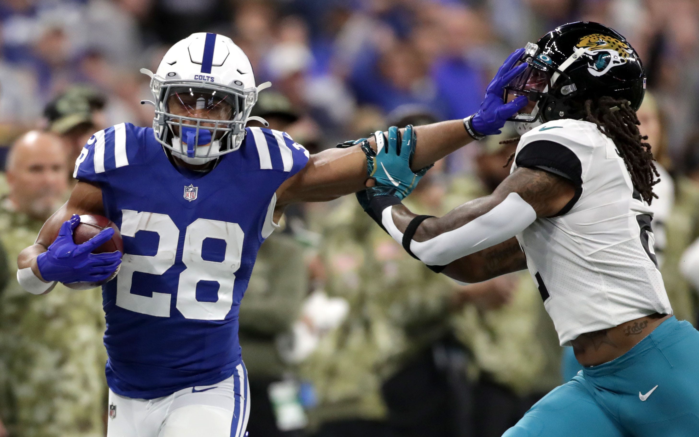 Colts running back Jonathan Taylor still arms Jacksonville Jaguars free safety Rayshawn Jenkins (right)