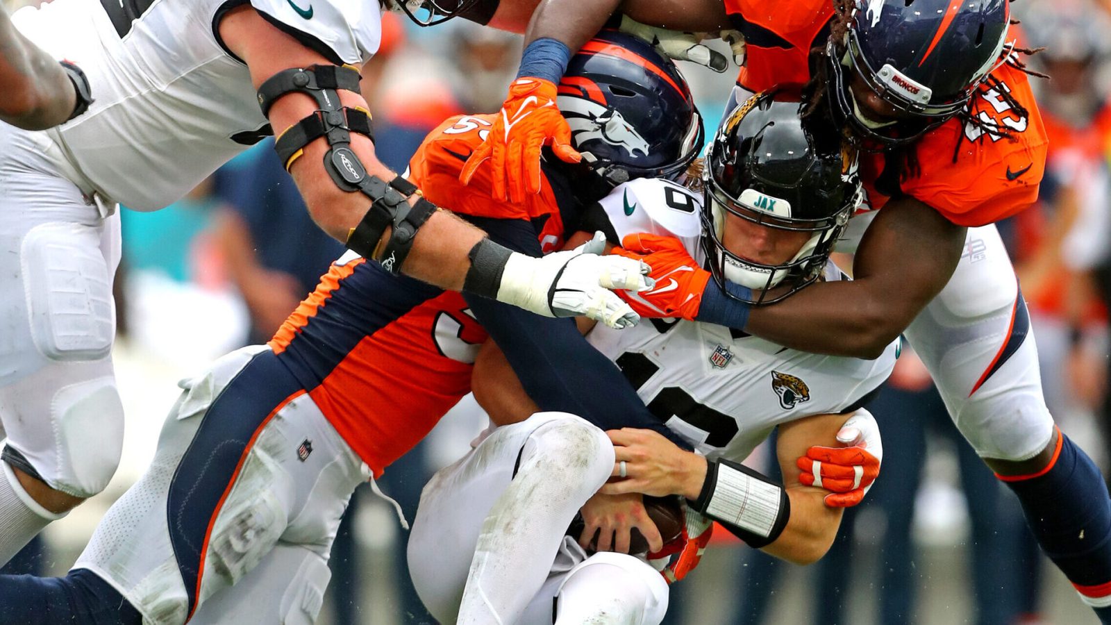 Jacksonville Jaguars quarterback Trevor Lawrence (middle) is sacked by Denver Broncos outside linebackers Von Miller (left) and A.J. Johnson (right)