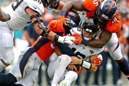 Jacksonville Jaguars quarterback Trevor Lawrence (middle) is sacked by Denver Broncos outside linebackers Von Miller (left) and A.J. Johnson (right)