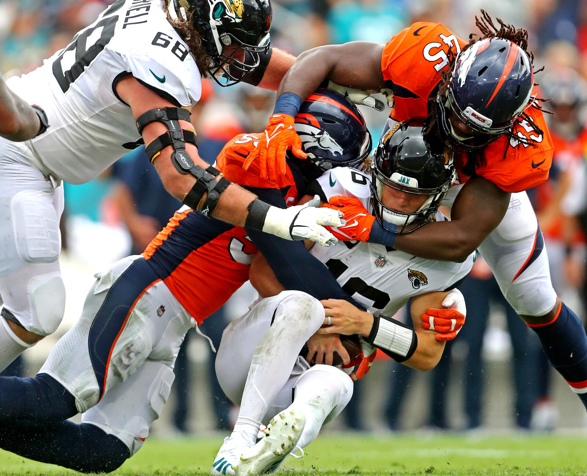 Jacksonville Jaguars quarterback Trevor Lawrence (middle) is sacked by Denver Broncos outside linebackers Von Miller (left) and A.J. Johnson (right)
