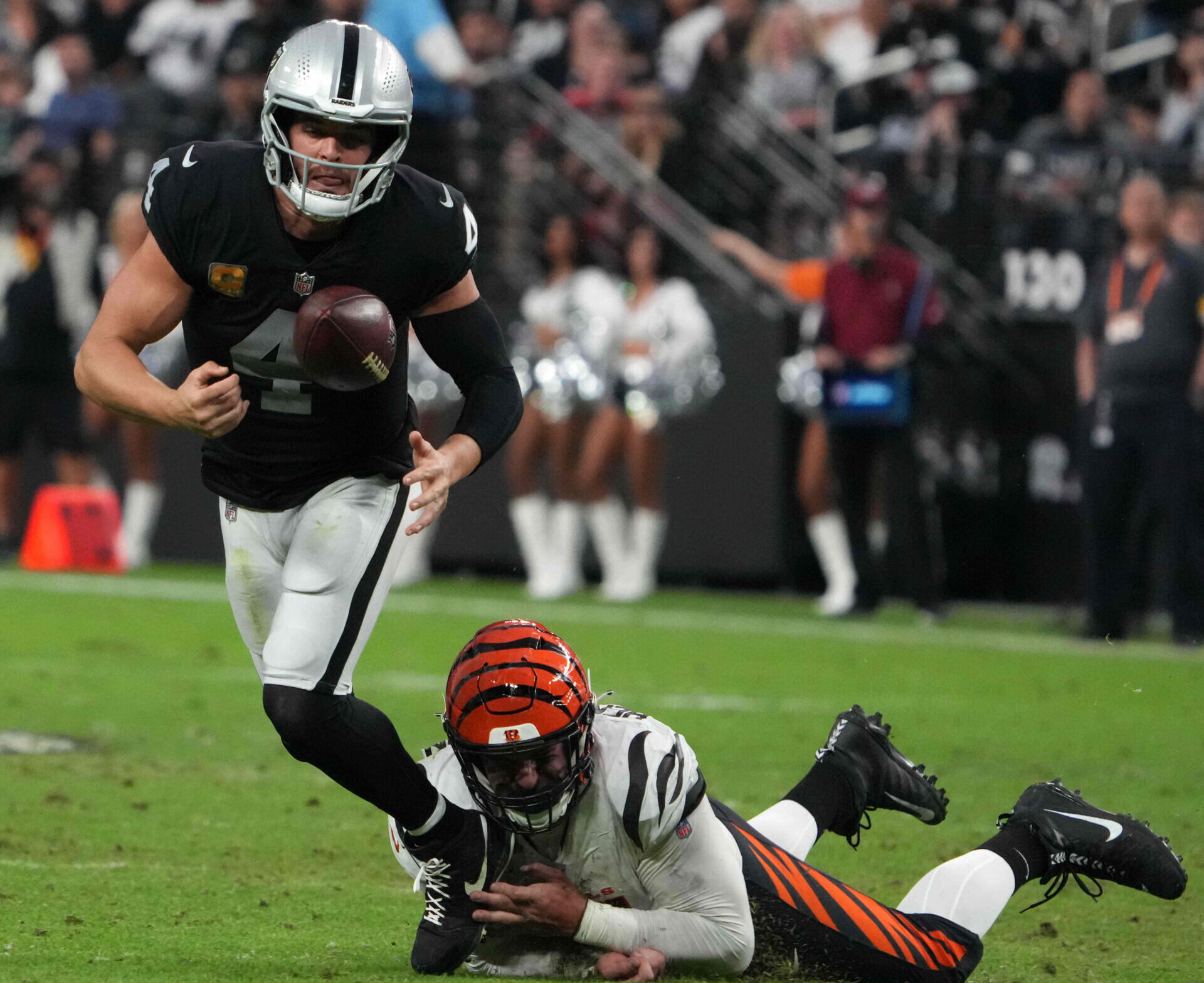 Cincinnati Bengals defensive end Trey Hendrickson (right) forces a fumble by Las Vegas Raiders quarterback Derek Carr (left)