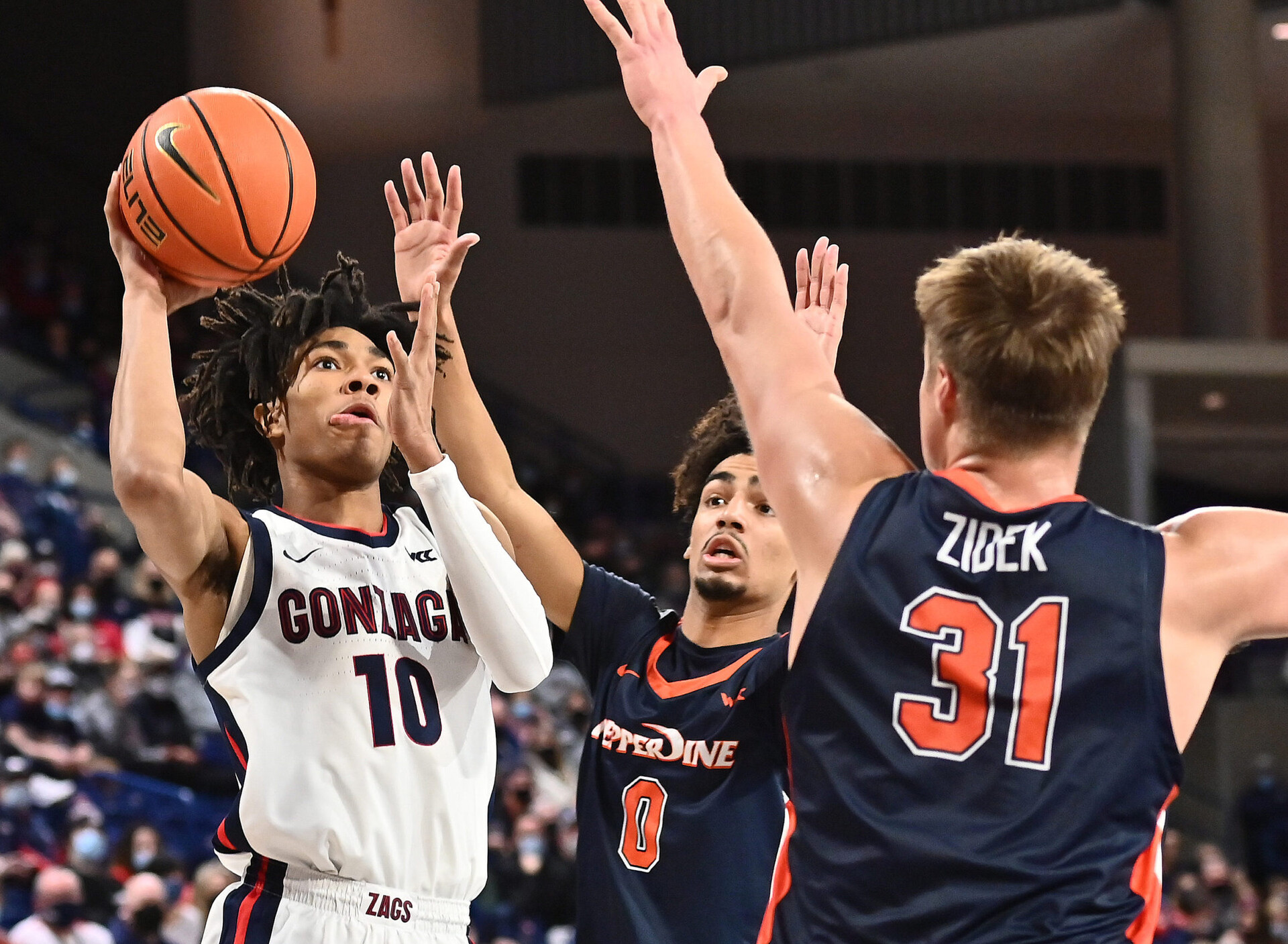 Gonzaga Bulldogs guard Hunter Sallis (left) shoots the ball over Pepperdine Waves guard Houston Mallette (middle) in a West Coast Conference basketball game