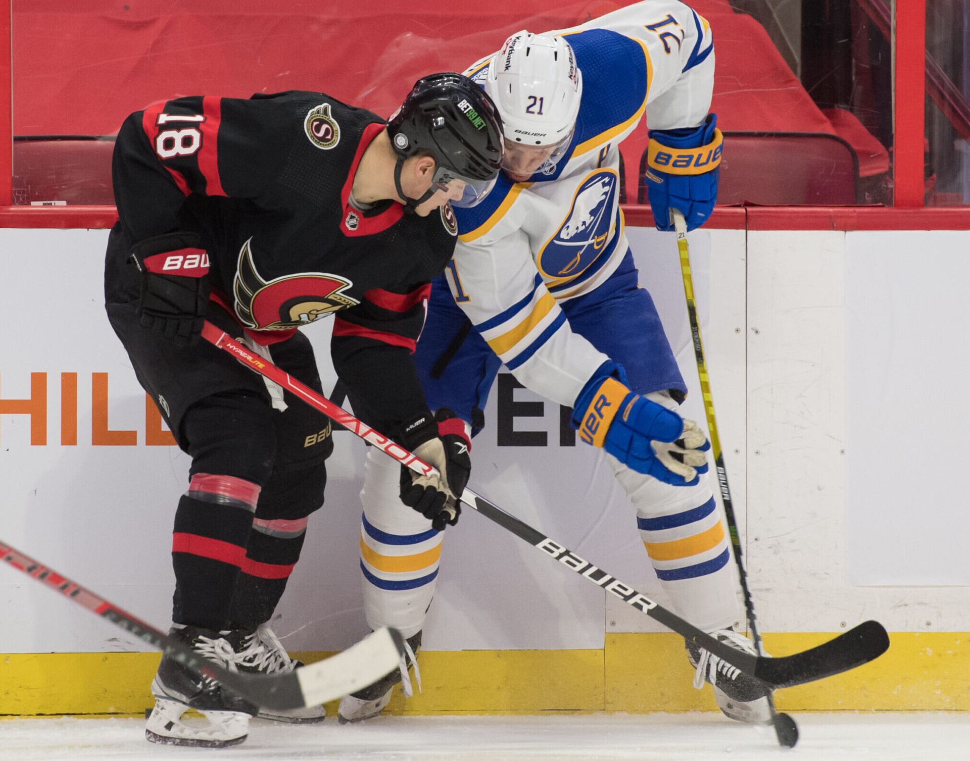 Ottawa Senators left wing Tim Stützle (left) battles for a loose puck with Buffalo Sabres right wing Kyle Okposo (right)