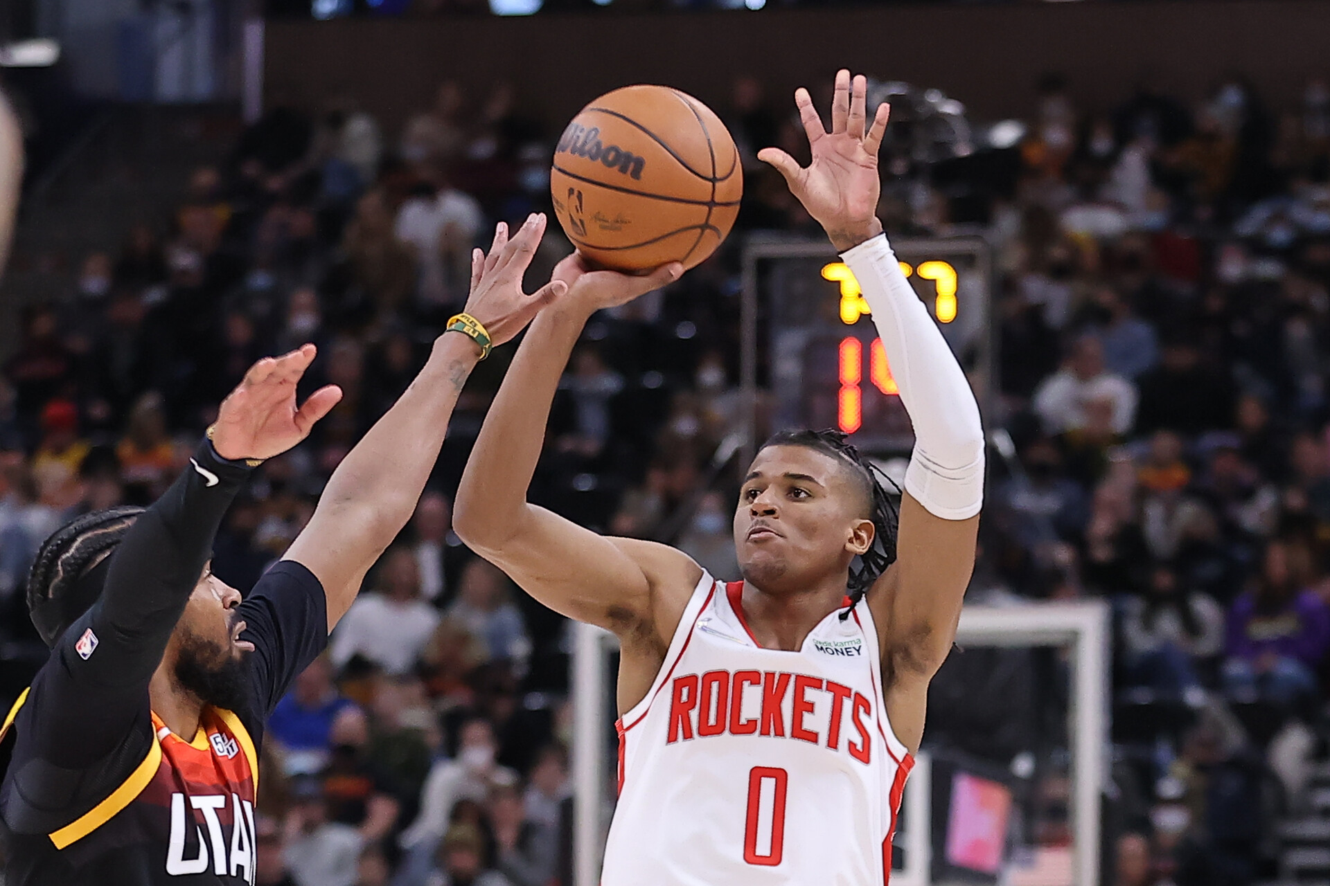 Houston Rockets guard Jalen Green (right) shoots and makes a three-point basket while being defended by Utah Jazz guard Mike Conley (left)