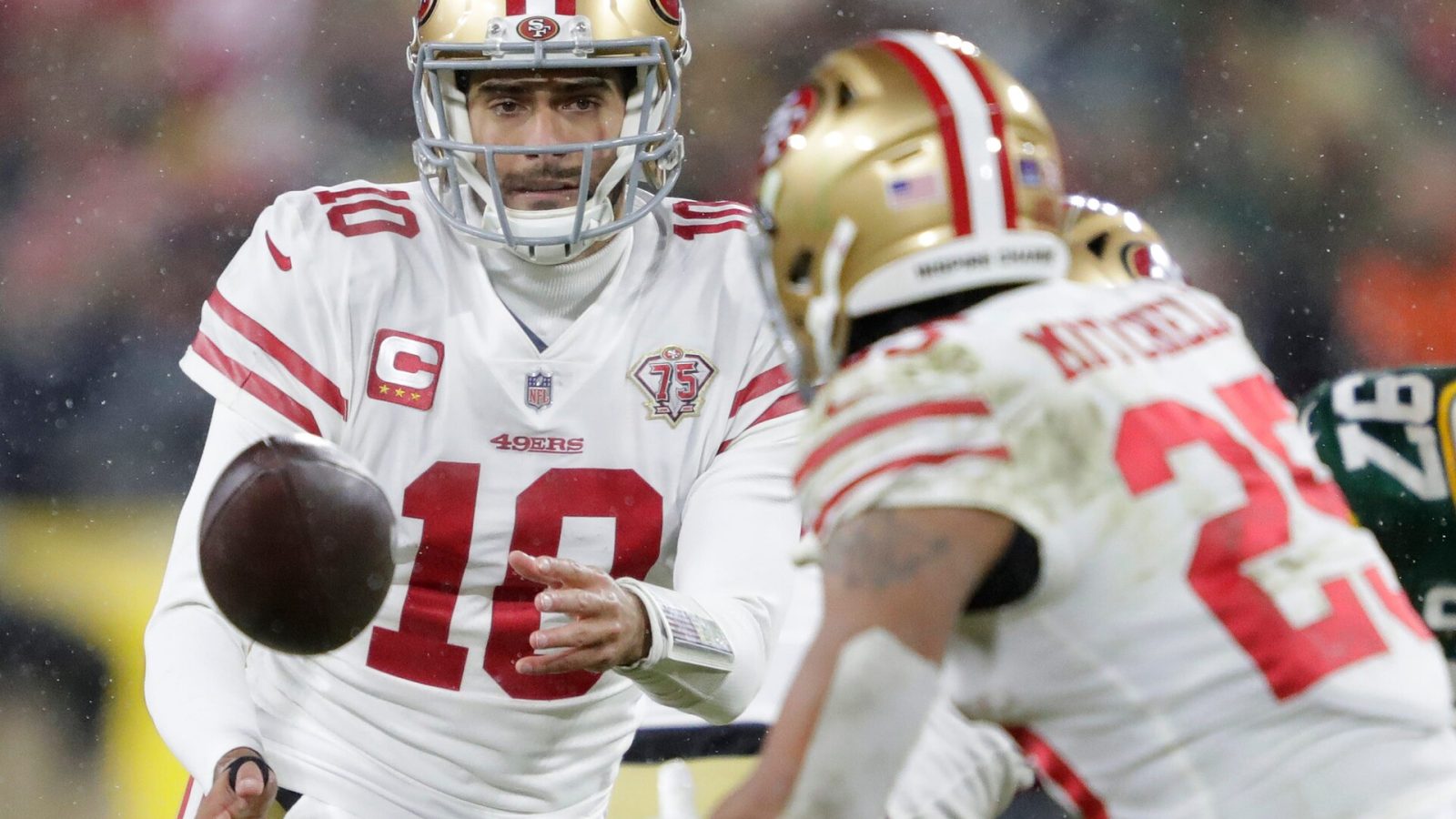 San Francisco 49ers quarterback Jimmy Garoppolo (10) tosses the ball top running back Elijah Mitchell (25) against the Green Bay Packers in the third quarter during their NFL divisional round football playoff game Saturday January 22, 2022, at Lambeau Field in Green Bay, Wis.