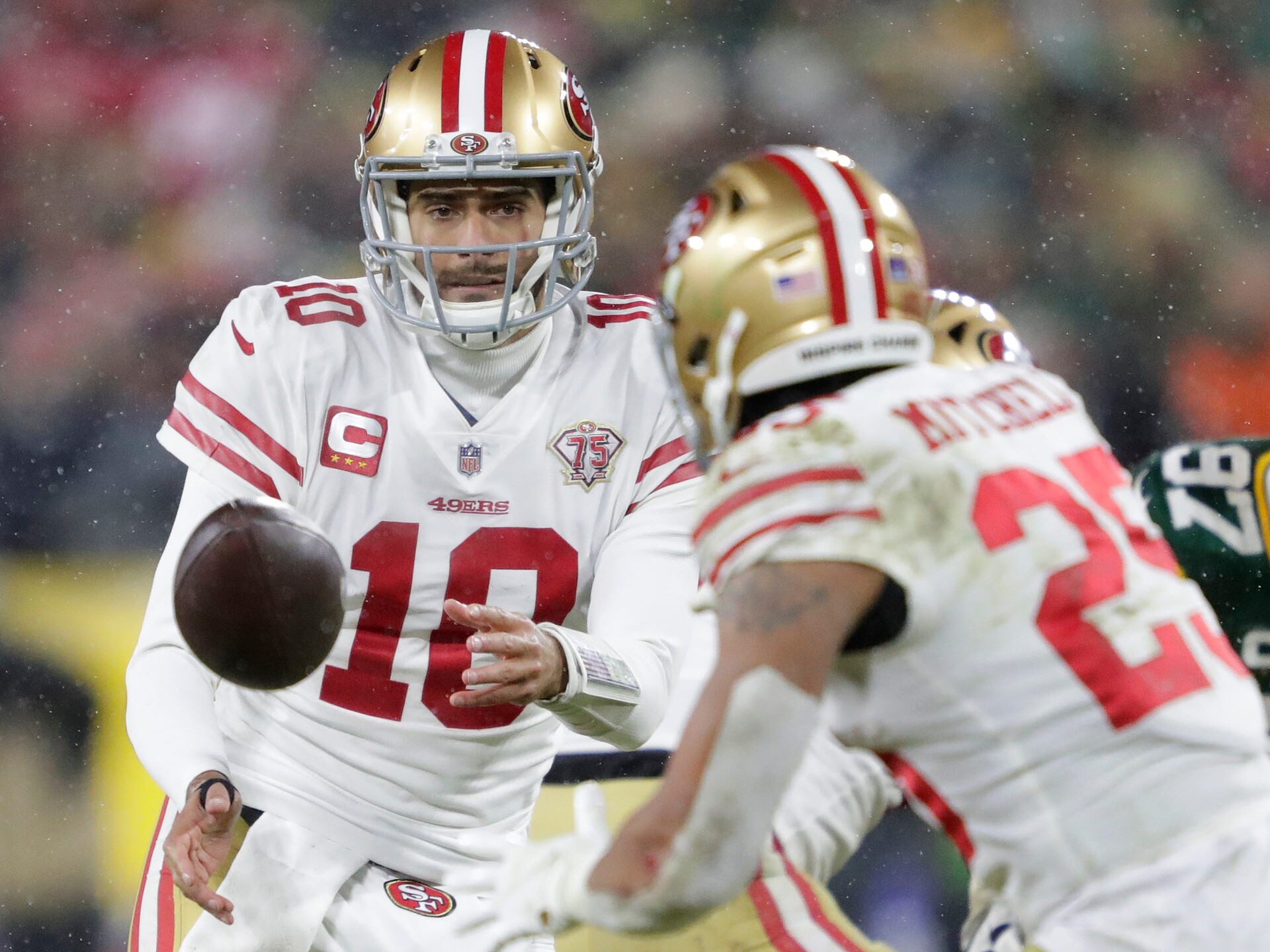 San Francisco 49ers quarterback Jimmy Garoppolo (10) tosses the ball top running back Elijah Mitchell (25) against the Green Bay Packers in the third quarter during their NFL divisional round football playoff game Saturday January 22, 2022, at Lambeau Field in Green Bay, Wis.