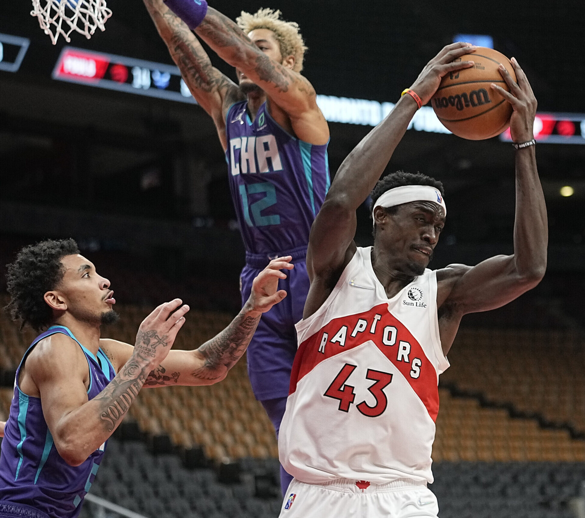 Toronto Raptors forward Pascal Siakam (right) grabs a rebound against Charlotte Hornets guard James Bouknight (left)