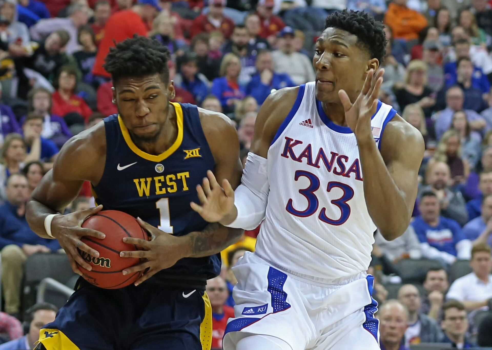 West Virginia Mountaineers forward Derek Culver (left) secures the basketball as he draws contact from Kansas Jayhawks forward David McCormack (right) during a Big 12 basketball game