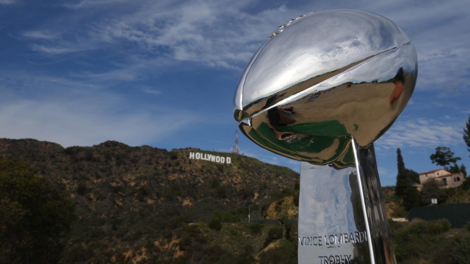 A photo of the Vince Lombardi trophy with the Hollywood sign visible in the distance