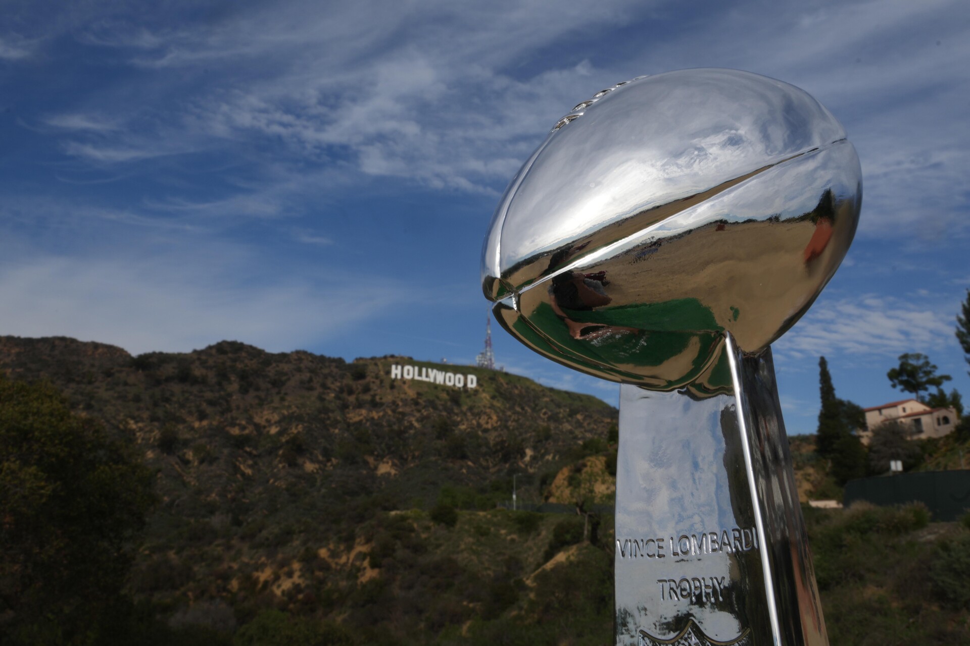 A photo of the Vince Lombardi trophy with the Hollywood sign visible in the distance