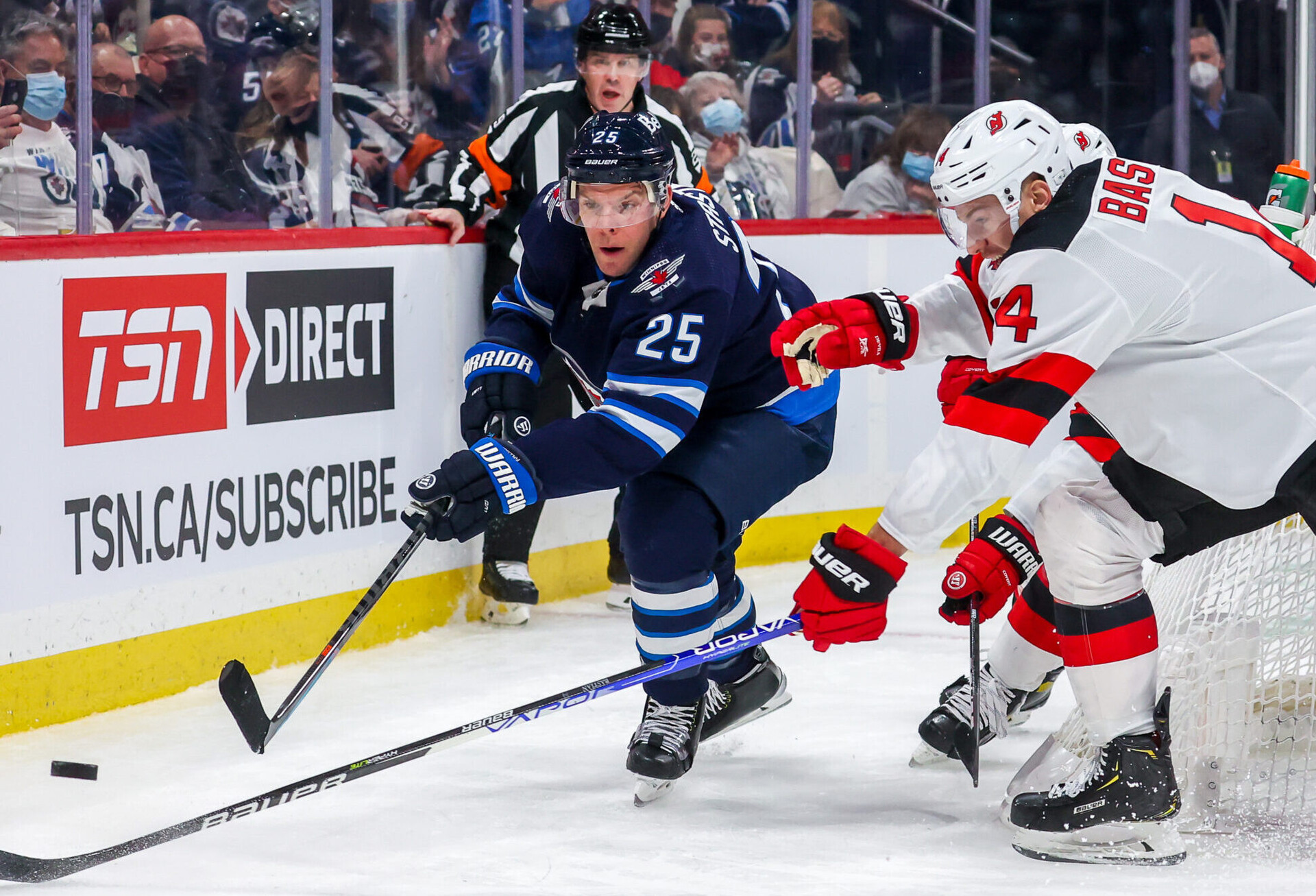 Paul Stastny #25 of the Winnipeg Jets plays the puck behind the net while Nathan Bastian #14 of the New Jersey Devils moves in to defend during second period action at Canada Life Centre on December 03, 2021 in Winnipeg, Manitoba, Canada.
