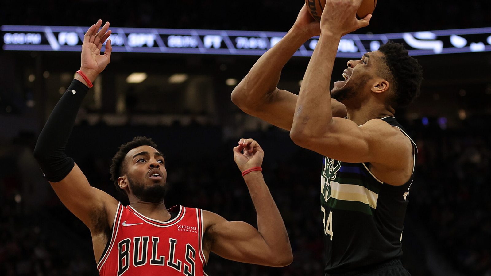 Milwaukee Bucks forward Giannis Antetokounmpo (right) holds the ball above his head while being guarded by the Chicago Bulls' Troy Brown Jr. (left)