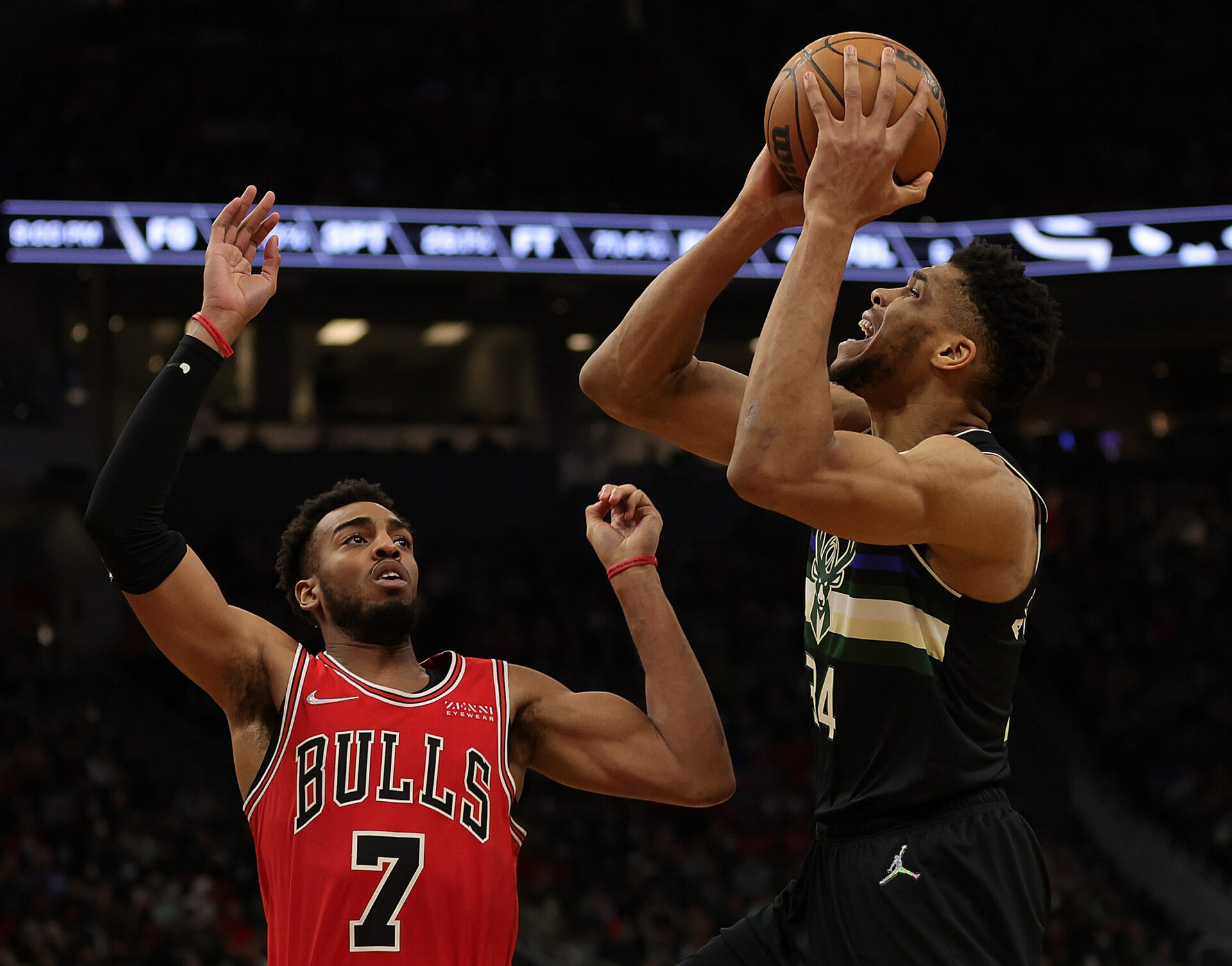 Milwaukee Bucks forward Giannis Antetokounmpo (right) holds the ball above his head while being guarded by the Chicago Bulls' Troy Brown Jr. (left)