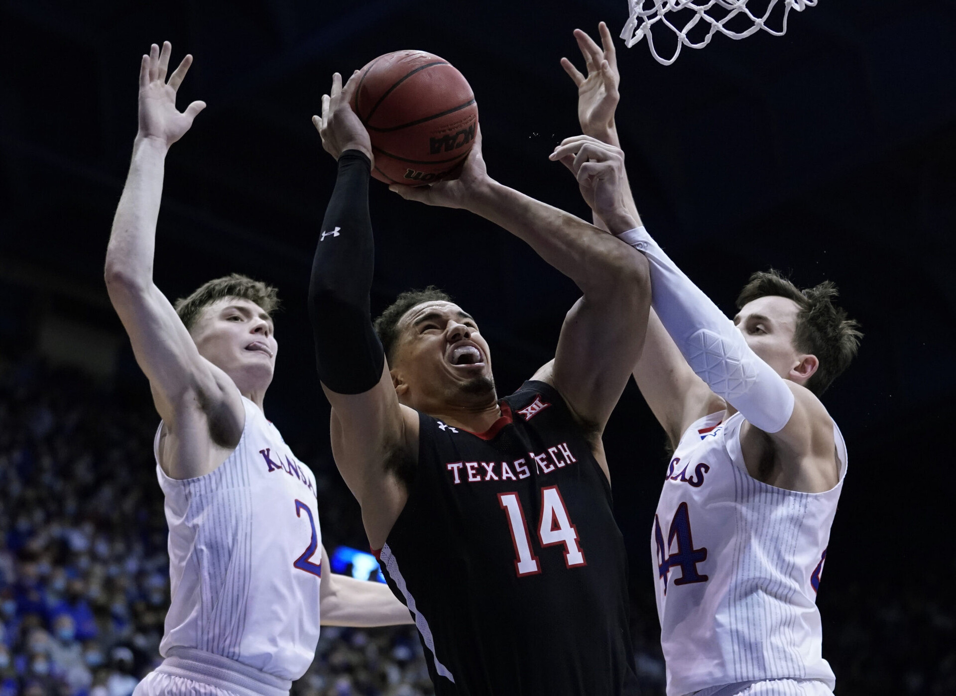 Texas Tech's Marcus Santos-Silva (center) goes up for a shot with both hands and is fouled while being defended by Kansas Jayhawks players Christian Braun (left) and Mitch Lightfoot (right) of the Kansas Jayhawks during a Big 12 basketball game