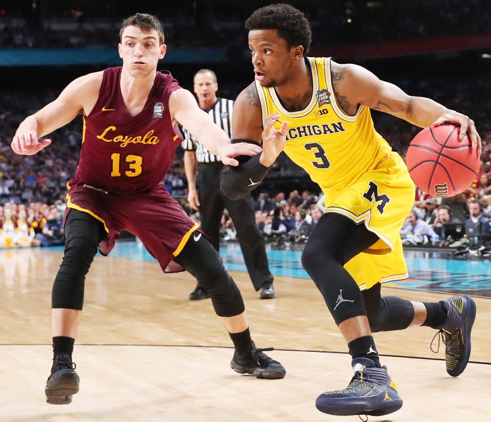 Michigan Wolverines guard Zavier Simpson (right) dribbles the ball with his left hand as he tries to work around Loyola Chicago defender Clayton Custer (left) during the 2018 Men's Final Four