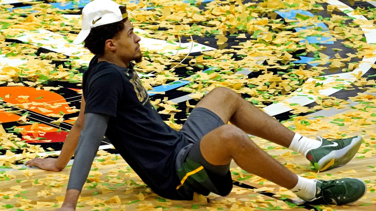 Baylor Bears guard MaCio Teague sits on a confetti-filled basketball court after Baylor beat the Gonzaga Bulldogs to win the 2021 NCAA Tournament championship