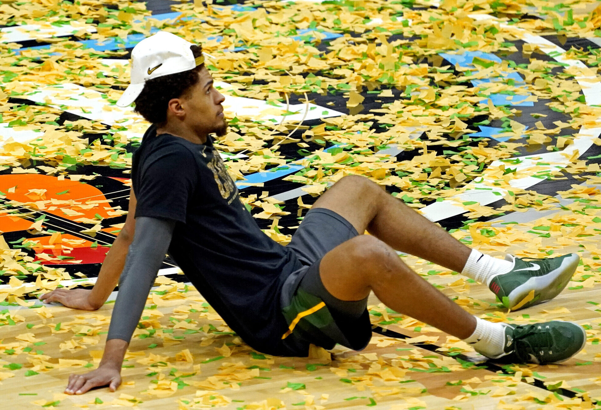 Baylor Bears guard MaCio Teague sits on a confetti-filled basketball court after Baylor beat the Gonzaga Bulldogs to win the 2021 NCAA Tournament championship