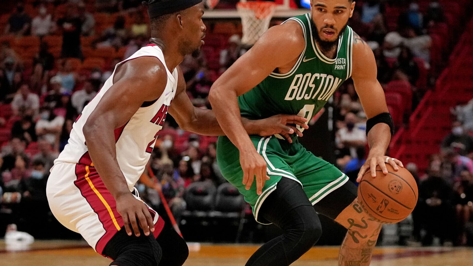 Boston Celtics forward Jayson Tatum (right) dribbles the ball with his left hand and tries to get around the defensive pressure applied by Miami Heat forward Jimmy Butler (left)