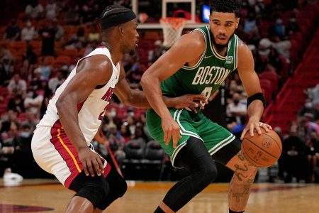 Boston Celtics forward Jayson Tatum (right) dribbles the ball with his left hand and tries to get around the defensive pressure applied by Miami Heat forward Jimmy Butler (left)