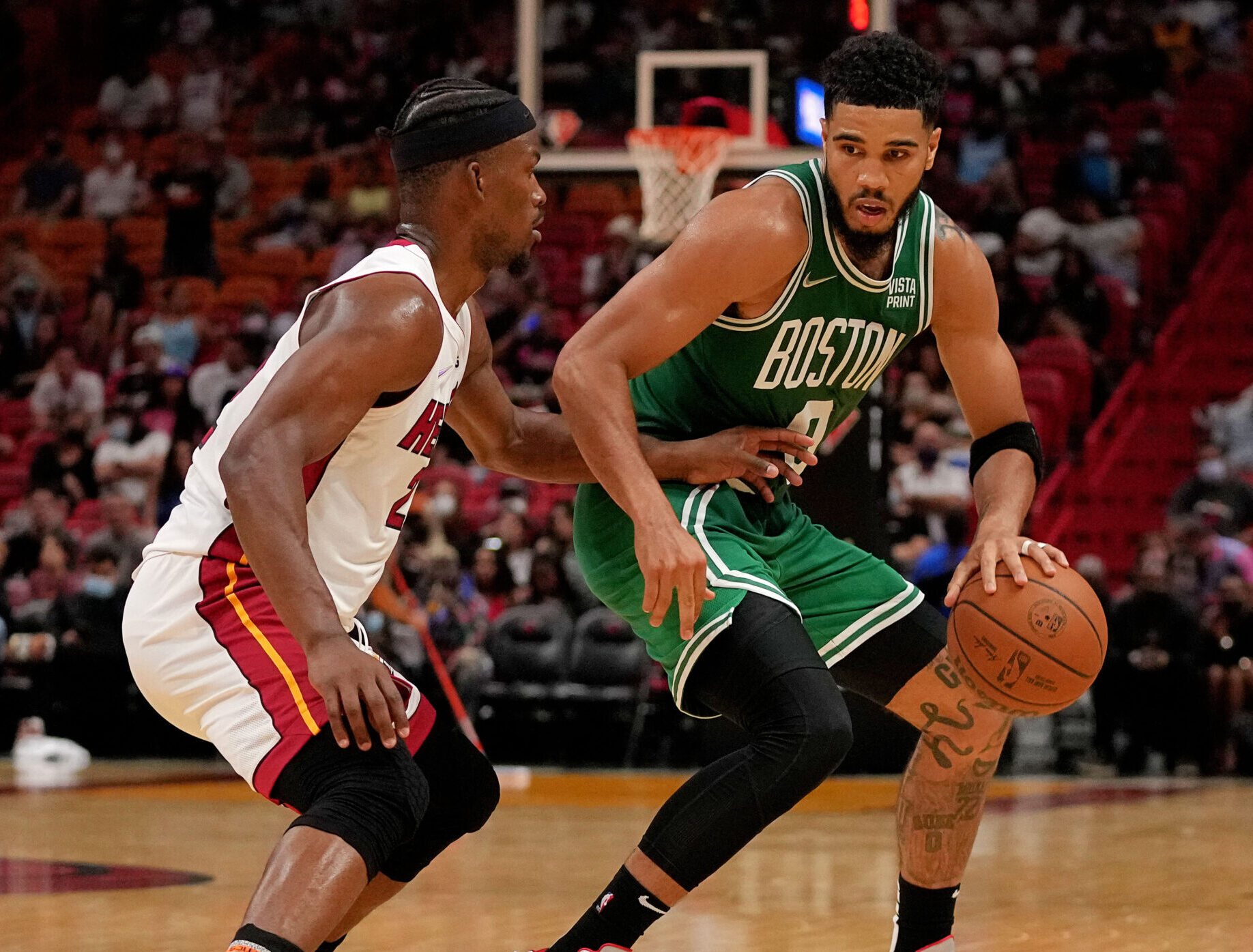 Boston Celtics forward Jayson Tatum (right) dribbles the ball with his left hand and tries to get around the defensive pressure applied by Miami Heat forward Jimmy Butler (left)