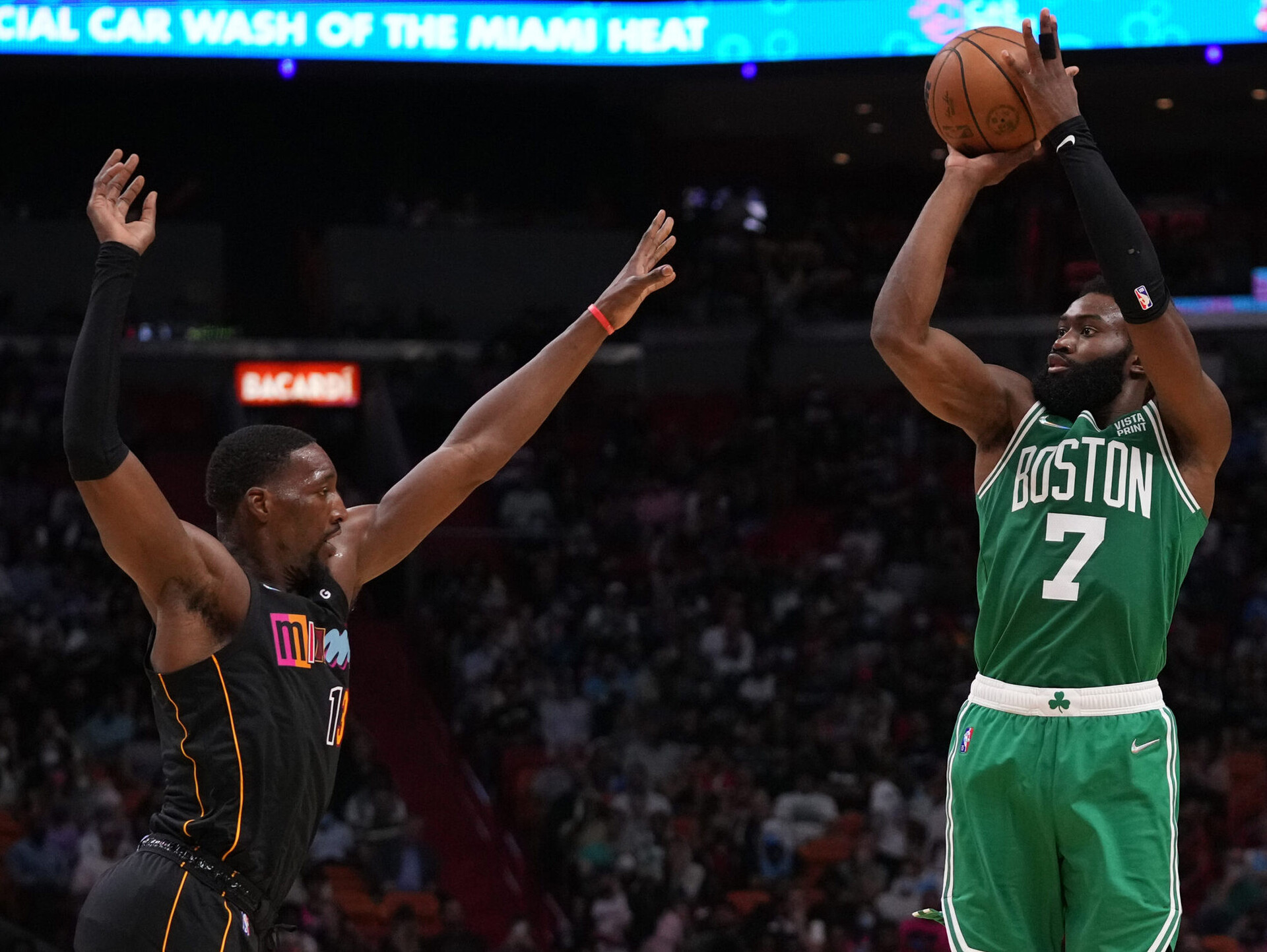Boston Celtics guard Jaylen Brown (right) rises up and shoots the basketball with his right hand over the outstretched left hand of leaping Miami Heat center Bam Adebayo (left)