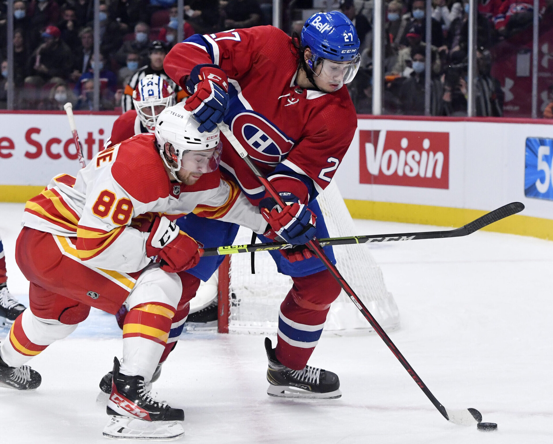 Calgary Flames forward Andrew Mangiapane (left) forechecks Montreal Canadiens defenseman Alexander Romanov (right) as both battle for the puck