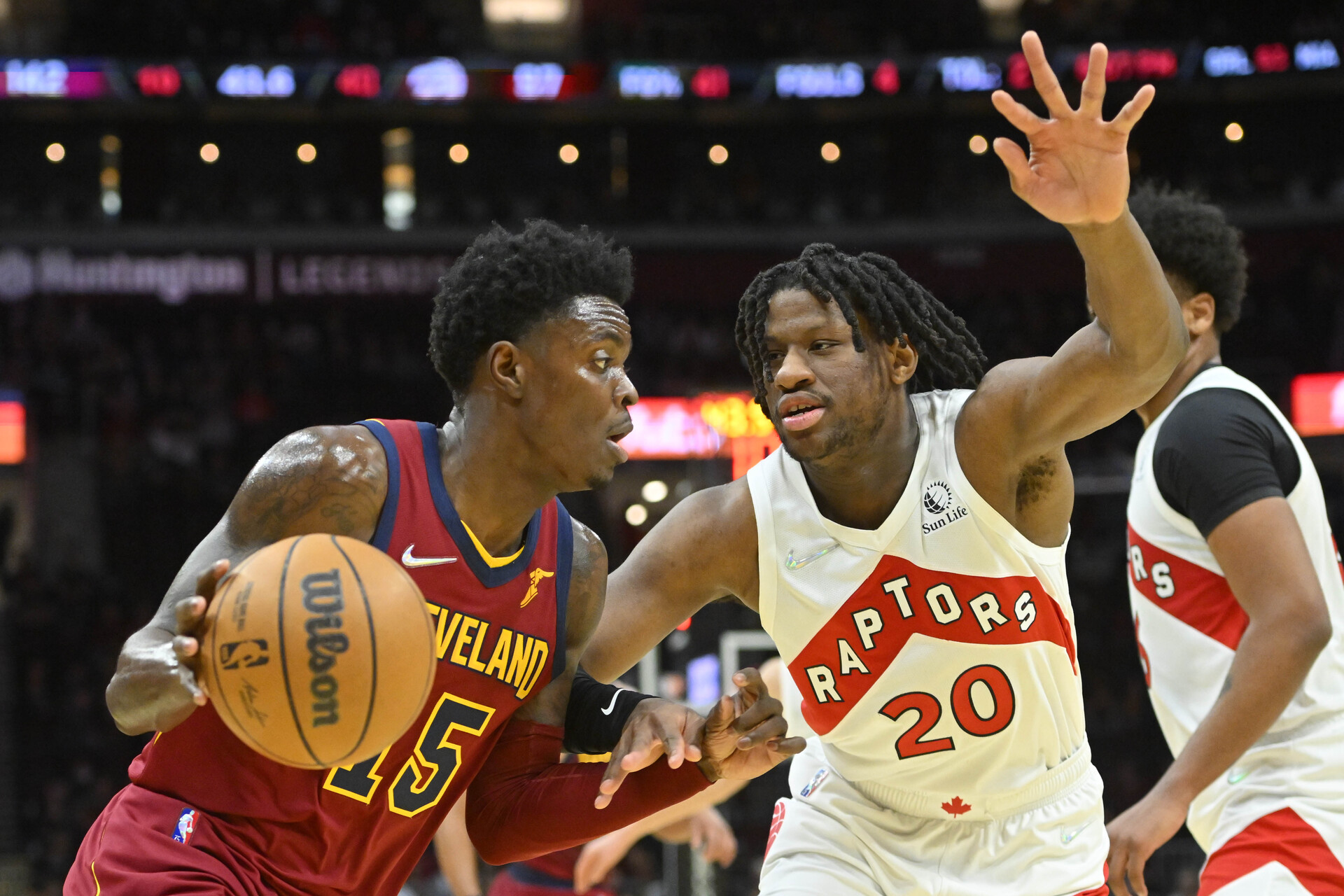 Cleveland Cavaliers forward Trevon Scott (left) dribbles the basketball with his right hand as he tries to get past defending Toronto Raptors center Daniel Oturu (right)