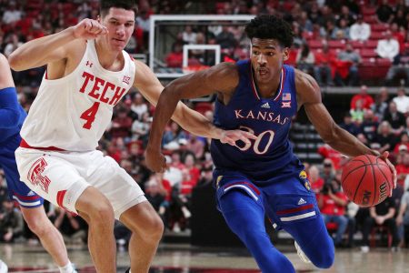Kansas Jayhawks guard Ohai Agbaji (right) dribbles the ball with his left hand as Texas Tech Red Raiders forward Daniel Batcho (left) plays defense during a Big 12 basketball game