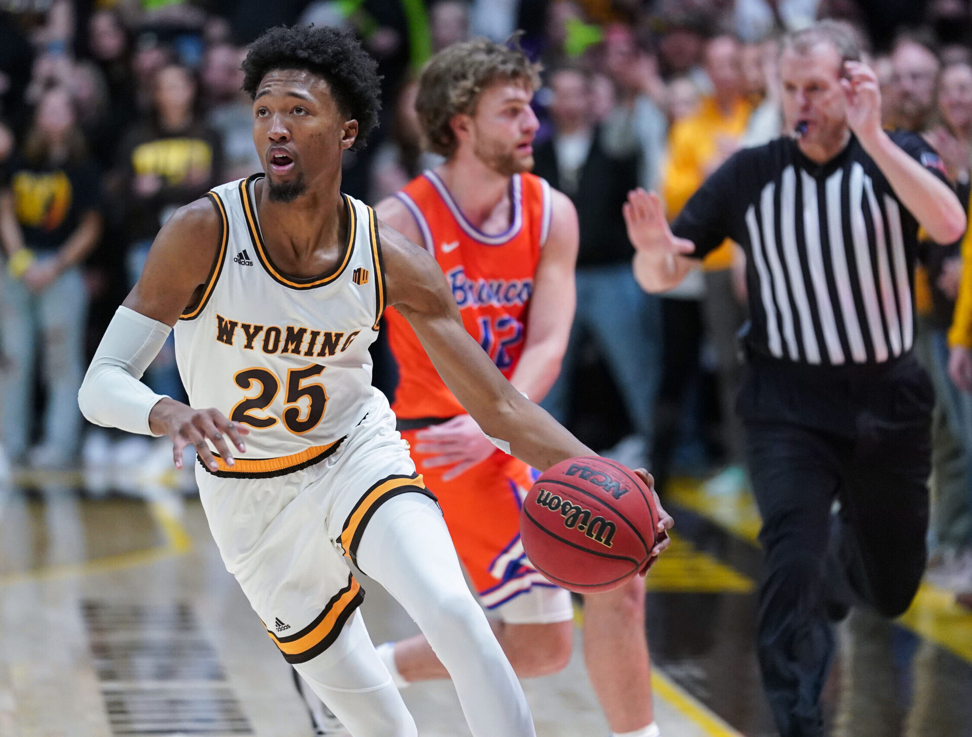 Wyoming Cowboys forward Jeremiah Oden (25) dribbles he ball with his left hand as a referee whistles a foul on Boise State Broncos guard Max Rice (background) during a Mountain West conference game