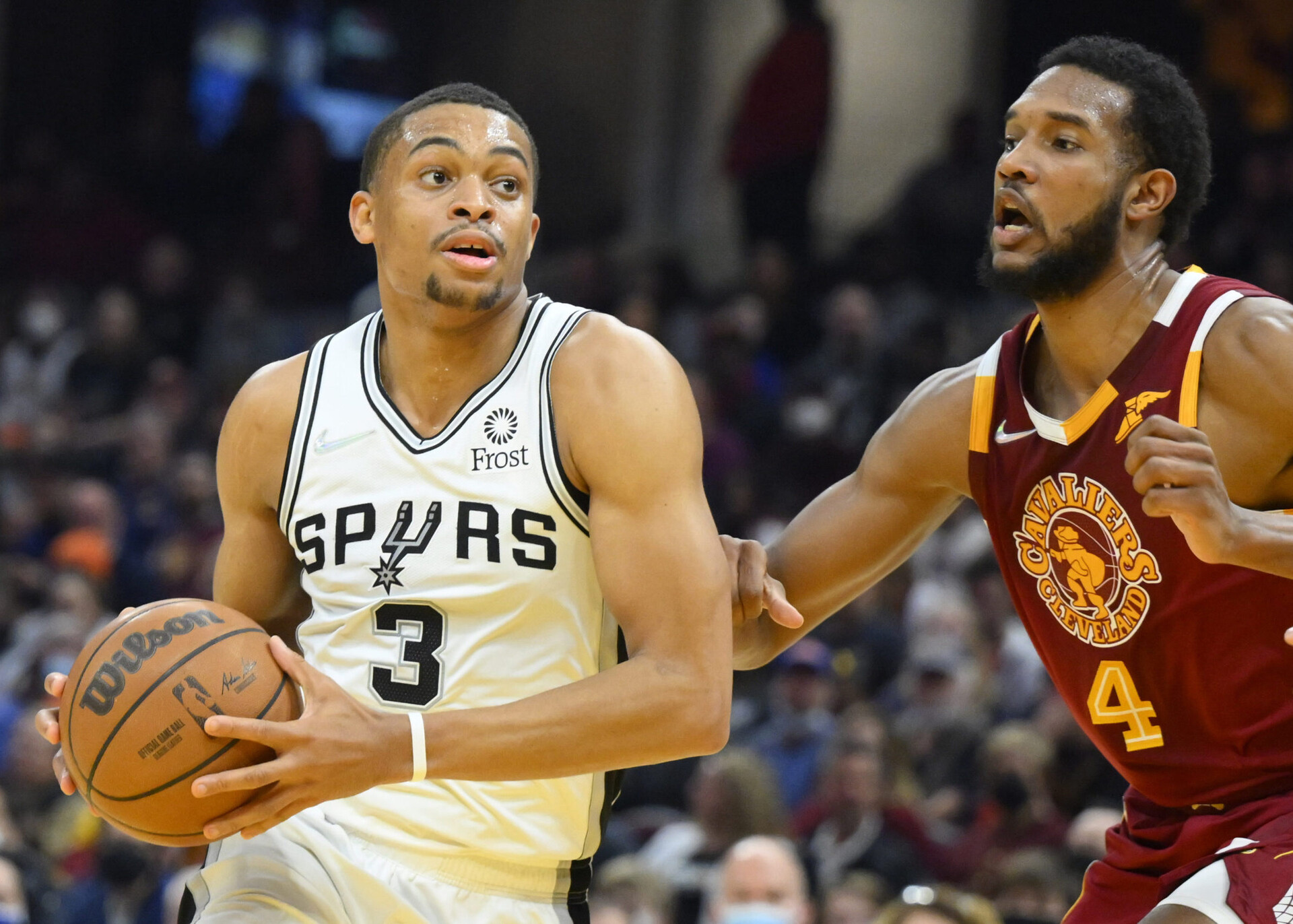 San Antonio Spurs forward Keldon Johnson (left) grasps the basketball with both hands as he drives to the hoop against defending Cleveland Cavaliers center Evan Mobley (right)