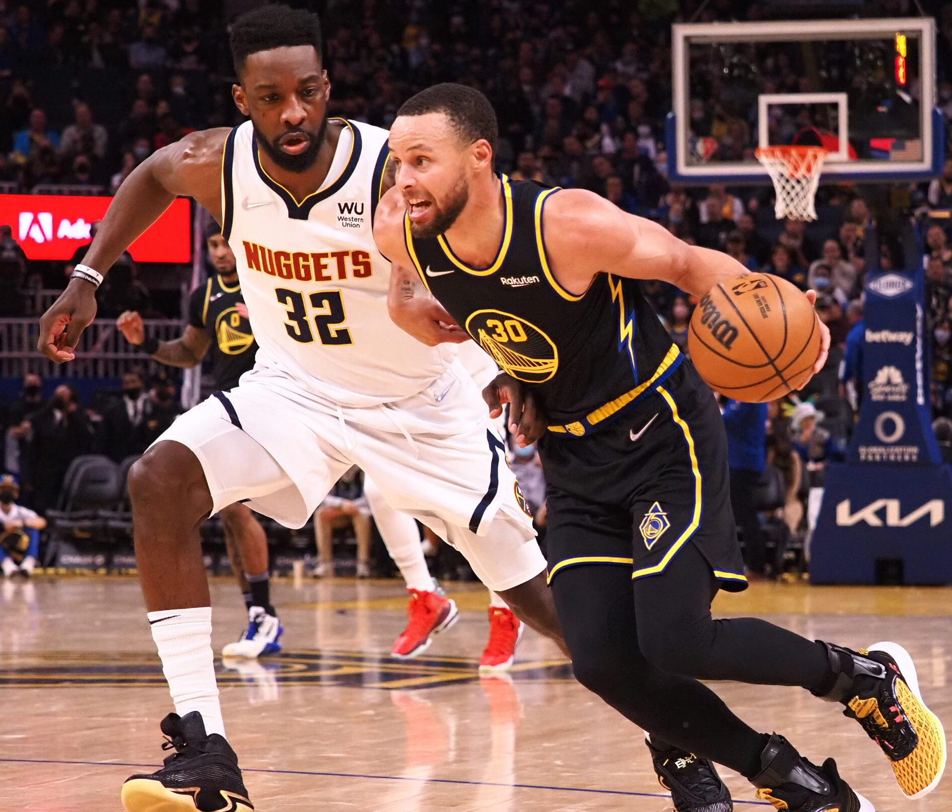 Golden State Warriors guard Stephen Curry (right) dribbles the ball with his left hand as he drives to the basket against Denver Nuggets forward Jeff Green