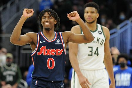 Philadelphia 76ers guard Tyrese Maxey (left) raises both arms with clenched fists in celebration of a win over the Milwaukee Bucks while Bucks center Giannis Antetokounmpo (right) looks on in the background