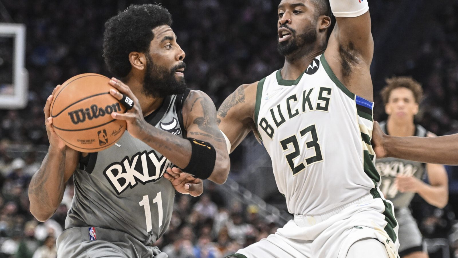Brooklyn Nets guard Kyrie Irving (left) controls the basketball with both hands while being defended by Milwaukee Bucks guard Wesley Matthews (right)