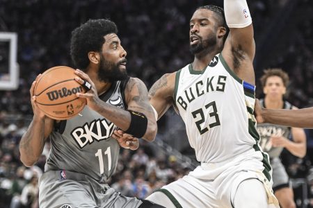 Brooklyn Nets guard Kyrie Irving (left) controls the basketball with both hands while being defended by Milwaukee Bucks guard Wesley Matthews (right)