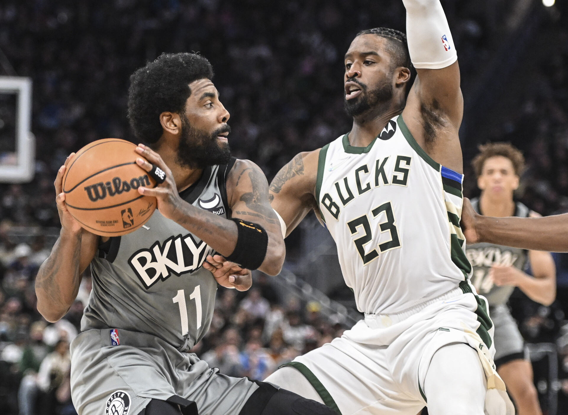 Brooklyn Nets guard Kyrie Irving (left) controls the basketball with both hands while being defended by Milwaukee Bucks guard Wesley Matthews (right)