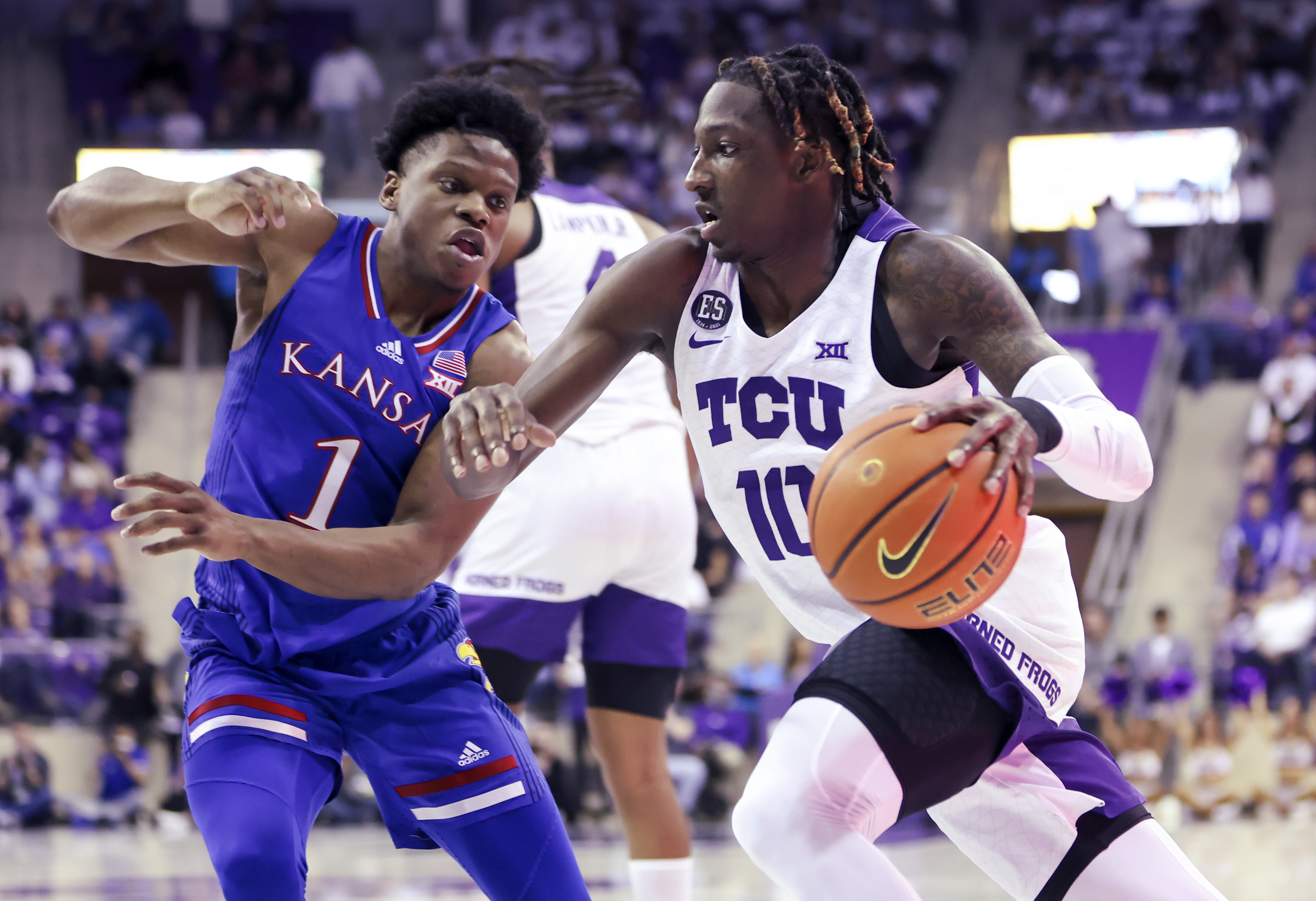 TCU Horned Frogs guard Damion Baugh (right) drives to the basket while dribbling the ball as Kansas Jayhawks guard Joseph Yesufu (left) defends during a Big 12 basketball game