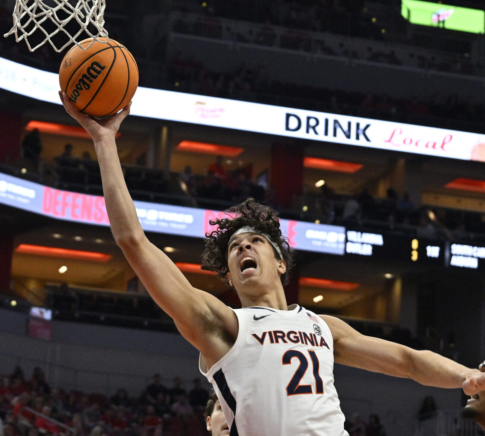 Virginia Cavaliers forward Kadin Shedrick (center) takes the basketball to the rim with his right hand as Louisville Cardinals forward Malik Williams (right) looks on during an ACC basketball game
