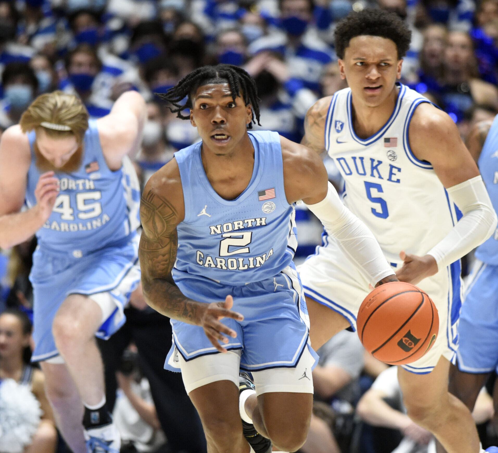 North Carolina Tar Heels guard Caleb Love (center) dribbles the ball up court as Duke forward Paolo Banchero (right) trails behind him during an ACC basketball game
