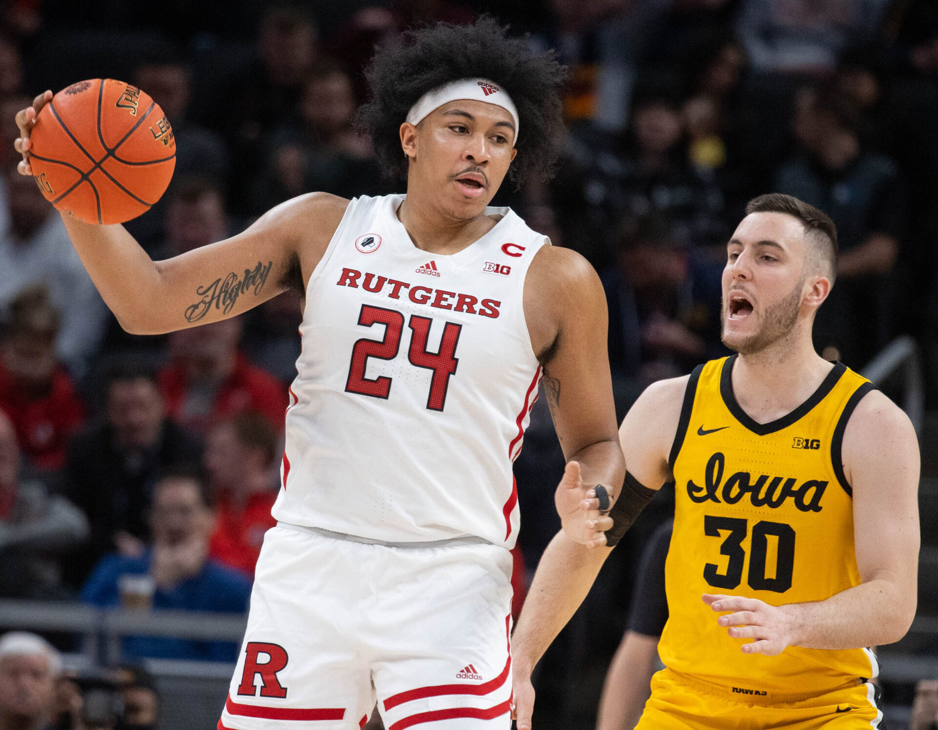 Rutgers Scarlet Knights forward Ron Harper Jr. (left) catches the basketball with his left hand while Iowa Hawkeyes guard Connor McCaffery (right) defends during a Big Ten Tournament basketball game