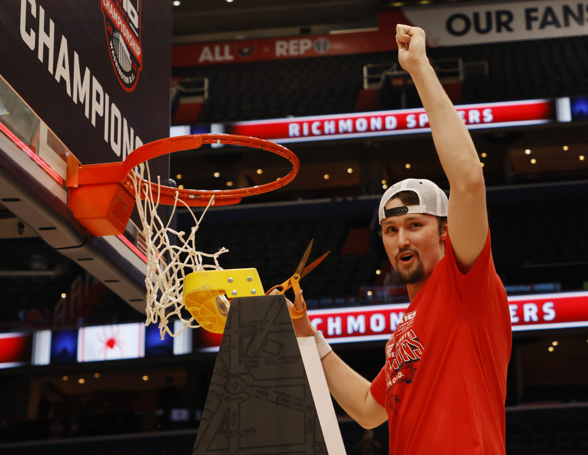 Richmond Spiders forward Matt Grace stands on a ladder and raises his right hand in celebration while cutting down the net after beating Davidson for the Atlantic-10 Conference tournament championship