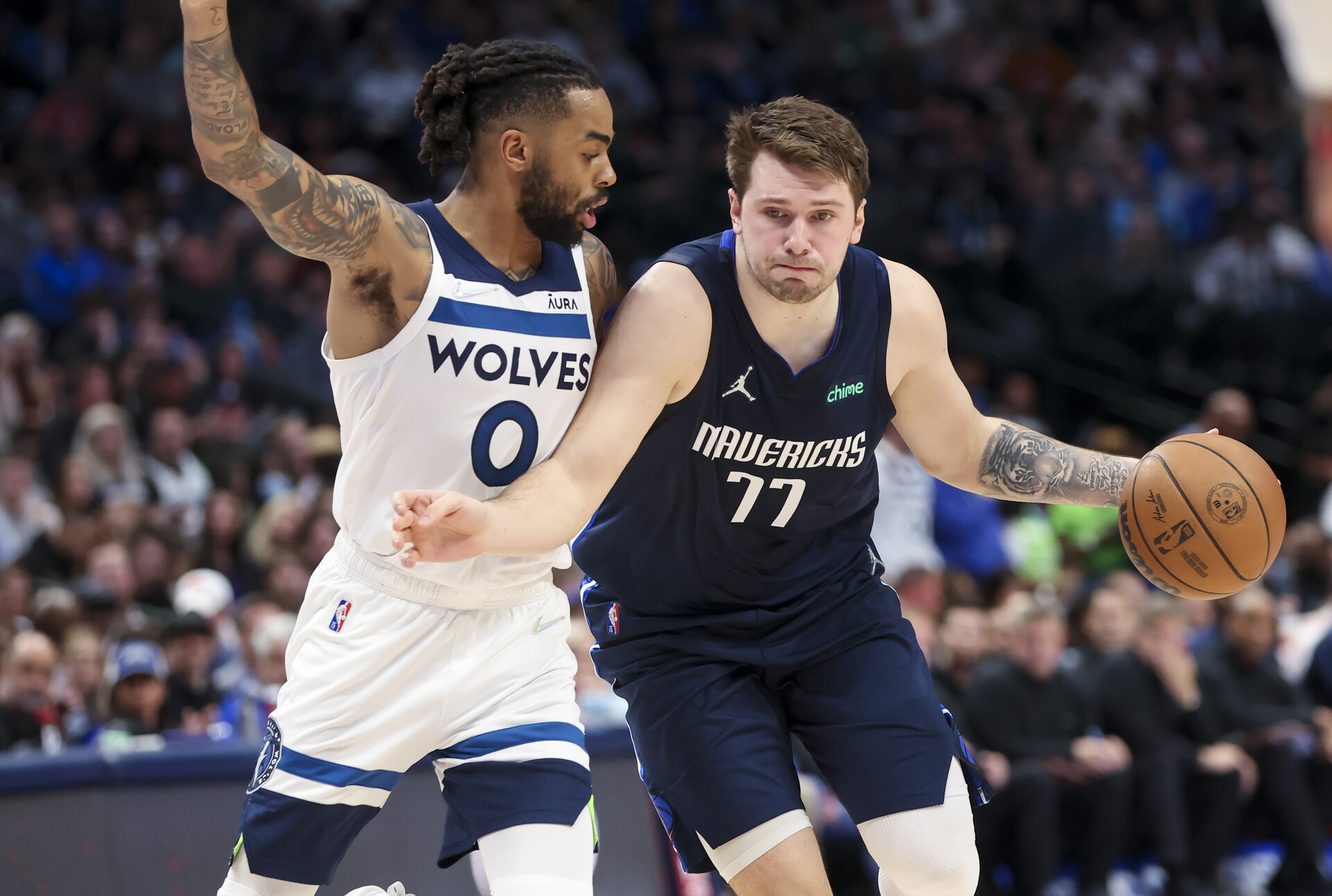 Dallas Mavericks guard Luka Doncic (right) dribbles the ball with his left hand and holds off Minnesota Timberwolves guard D'Angelo Russell (left) with his right arm as he drives to the basket