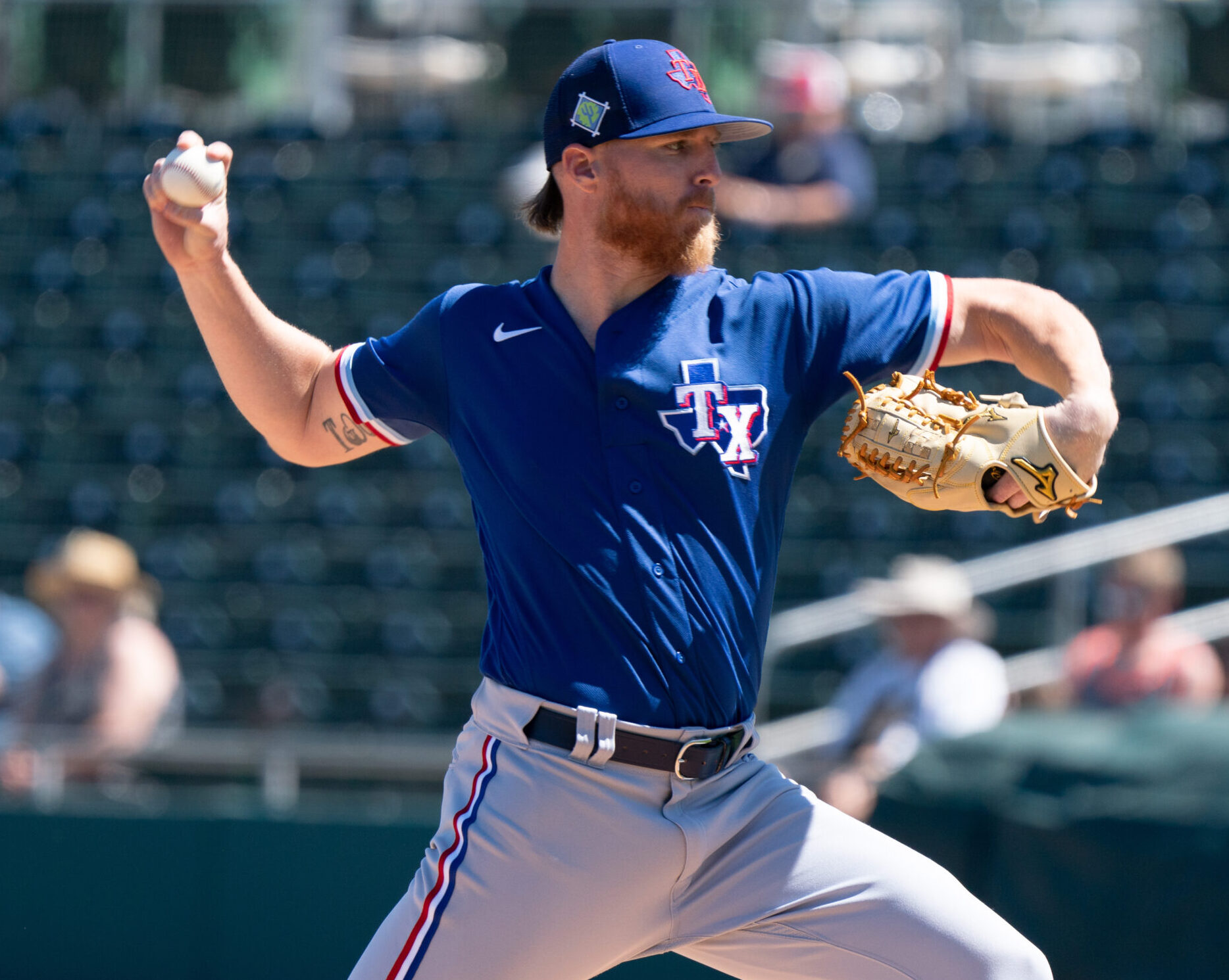 Texas Rangers right-handed pitcher Jon Gray reaches back to throw a. pitch during a spring training game against the Oakland Athletics