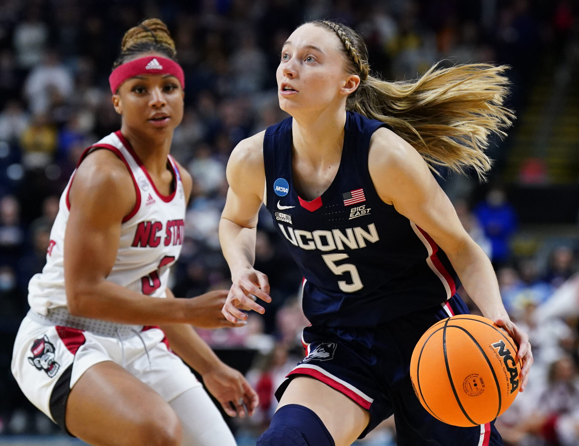 UConn Huskies guard Paige Bueckers (right) dribbles the basketball with her left hand as she drives to the basket against NC State Wolfpack forward Jada Boyd (left) during the Bridgeport regional finals of the women's college basketball NCAA Tournament