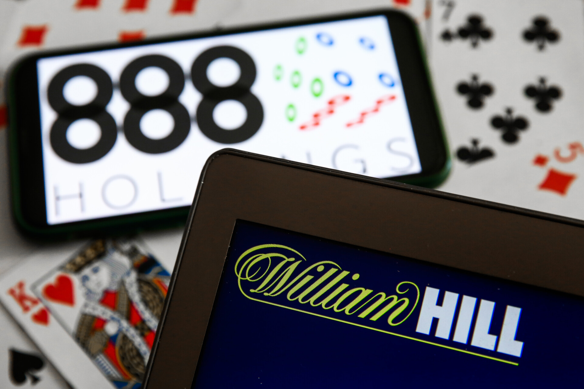 888 Holdings logo displayed on a mobile phone, William Hill logo displayed on a laptop screen