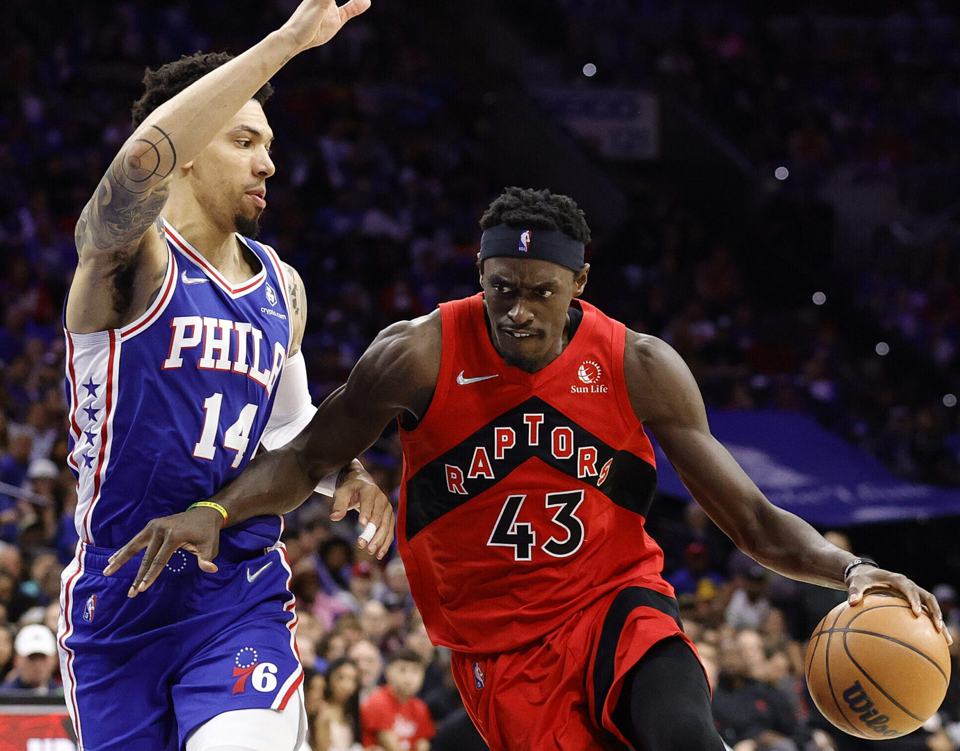 Toronto Raptors center Pascal Siakam (right) dribbles the basketball with his left hand and uses his right forearm to hold off defending Philadelphia 76ers forward Danny Green (left) during a first-round NBA playoff game