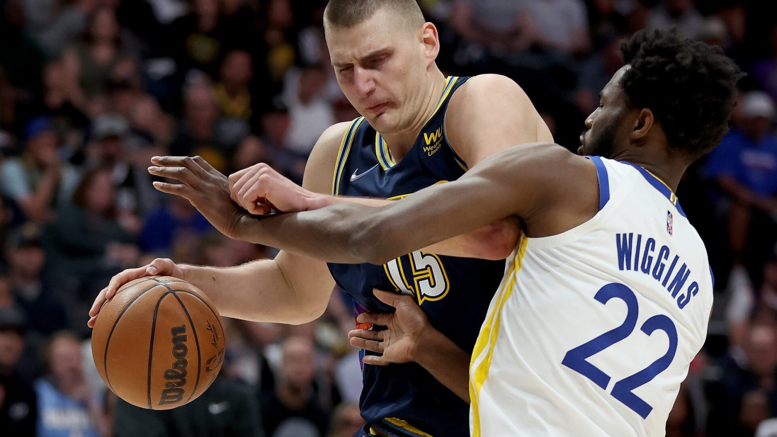 Denver Nuggets center Nikola Jokic, left, dribbles with his right hand while driving against Golden State Warriors forward Andrew Wiggins on Sunday, April 24, 2022, in Denver.